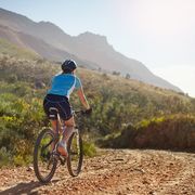 Cyclist riding a dirt road on the side of a mountain