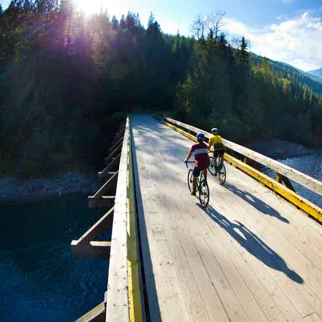 cyclists riding over a flat bridge