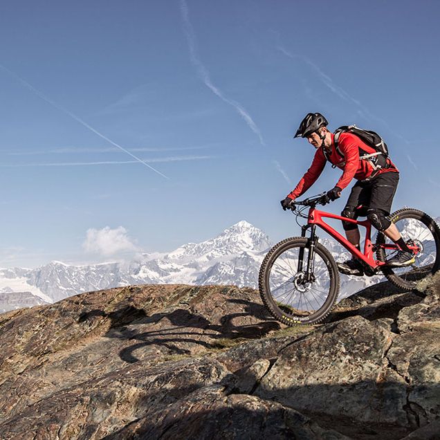 Rider on DT Swiss XRC 1200 Spline 25 wheels riding on boulders with mountains in the background