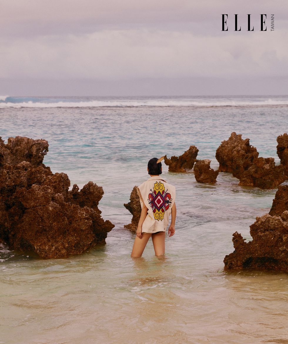 一個女人穿著刺繡背心站在海中