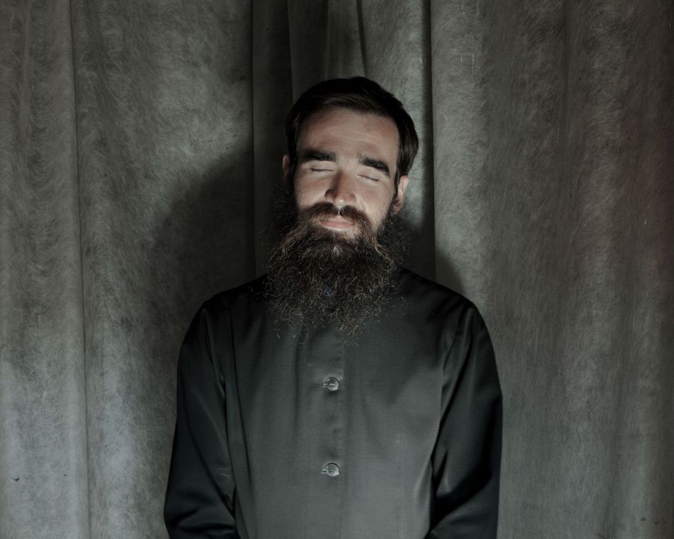 Dmitrij Polevtsjoek die de traditionele lange baard van Russischorthodoxe oudgelovigen draagt ontspant na een vijf uur durende gebedsdienst in de voorgaande nacht