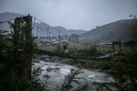 La Puria ligt een halve dag lopen van het dichtstbijzijnde stadje in het hooggelegen nevelwoud van Colombia Op deze foto loopt een vrouw over de enige brug die het dorp met de weg verbindt
