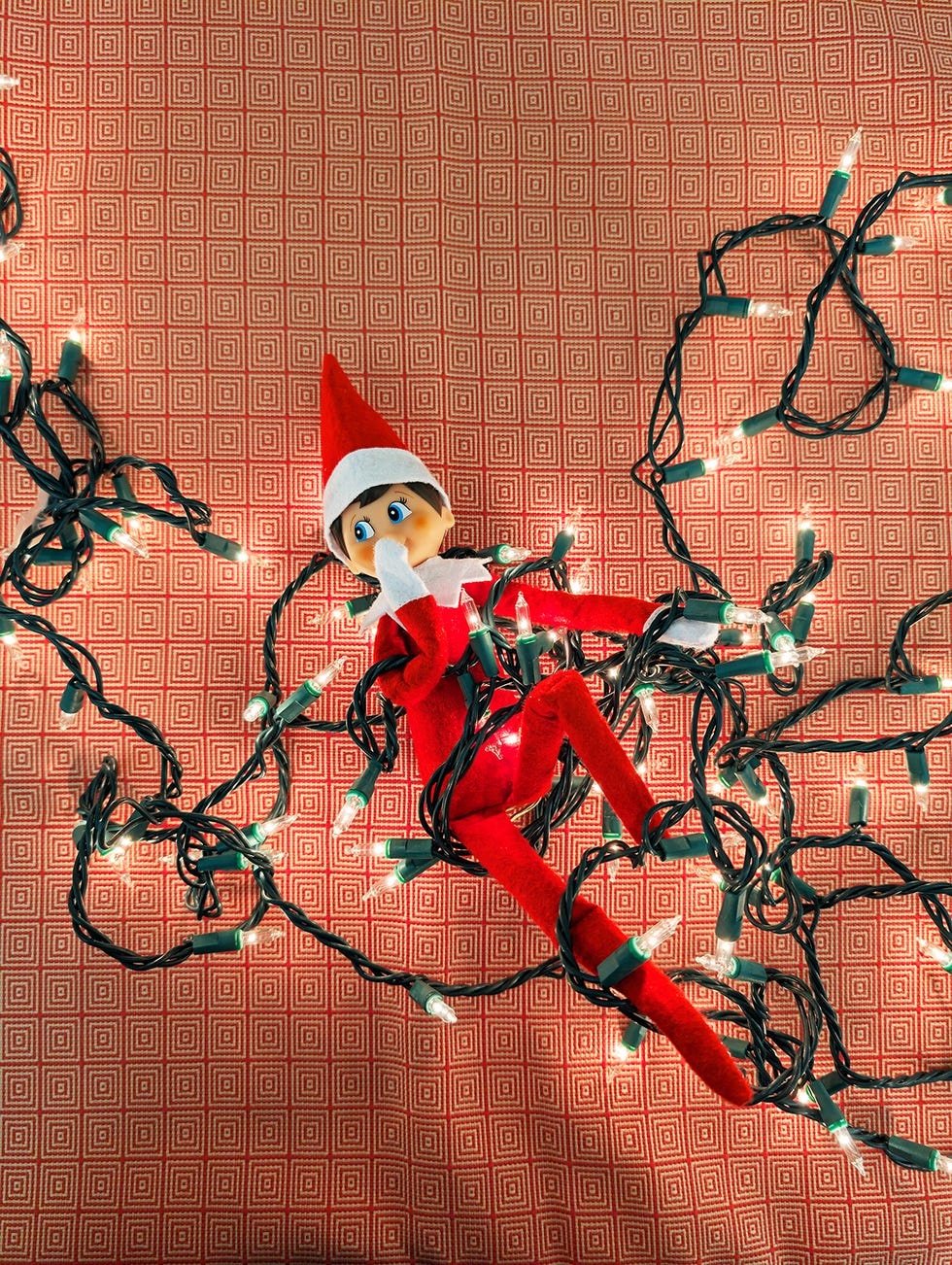 an elf on the shelf gets tangled in christmas lights