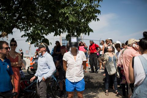 Een vrouw draagt een lasmasker om haar ogen te beschermen terwijl ze in Red Hook in Brooklyn New York naar de gedeeltelijke zonsverduistering kijkt