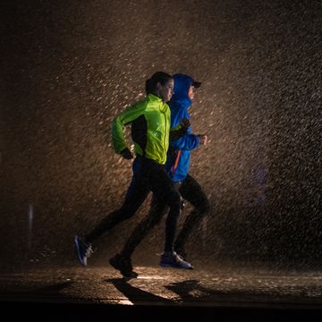 twee hardlopers lopen in het donker en regen