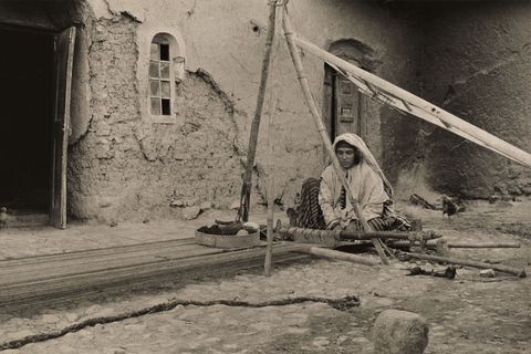 In de Perzische streek Dehbid vervaardigt een Quashquaivrouw een tapijt aan haar weefgetouw 1921