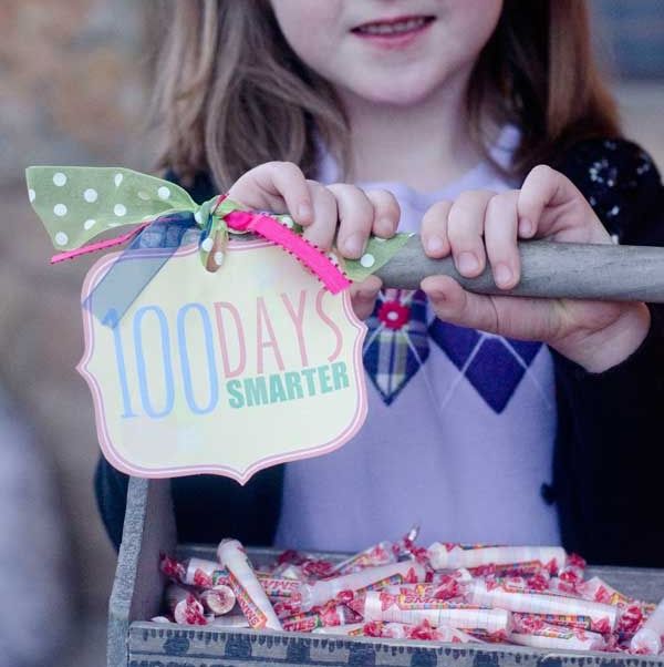 girl holds a box of smarties with a sign that says "100 days smarter"