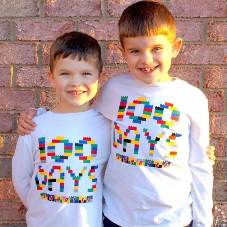 two boys standing next to each other wearing shirts that say "100 days smarter" out of felt lego blocks