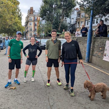 four individuals in casual athletic clothing with a dog standing on a street four individuals in casual athletic clothing with a dog standing on a street