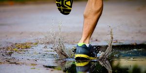 man's foot running, splashing in a puddle