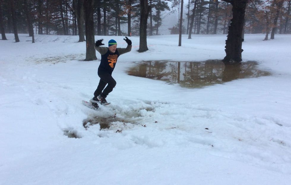 Runner in snow shoes jumping a wet area on the course 