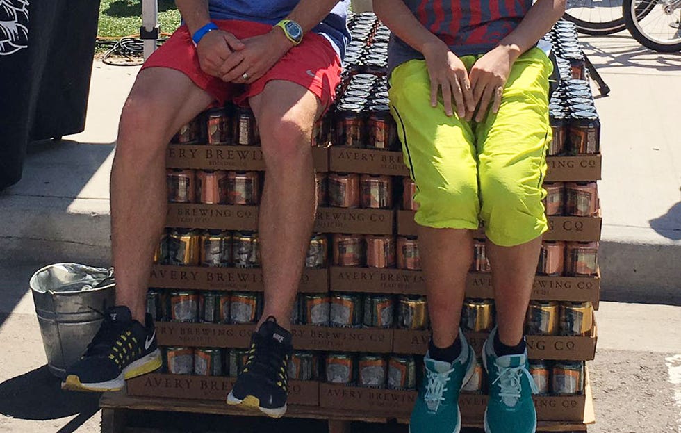 the legs of two runners sitting on many cases of beer.