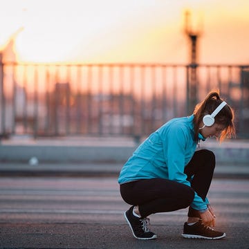 Woman stopping to tie shoes mid-run Woman stopping to tie shoes mid-run