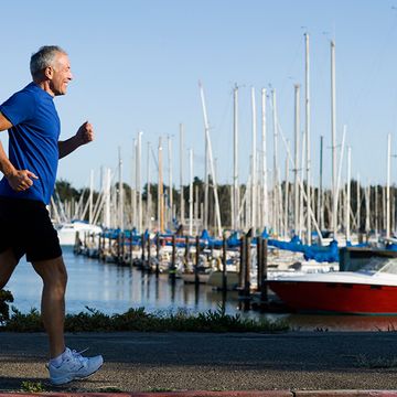 An 60-year-old man running along a marina.