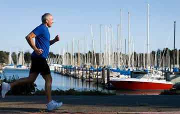 An 60-year-old man running along a marina.