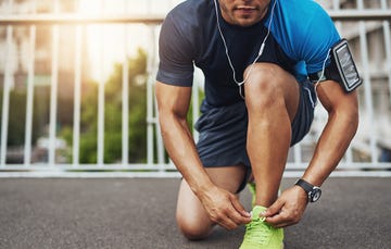 man tying shoes before running with music