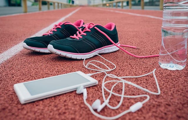 running shoes, an iPhone, and a water bottle on a track