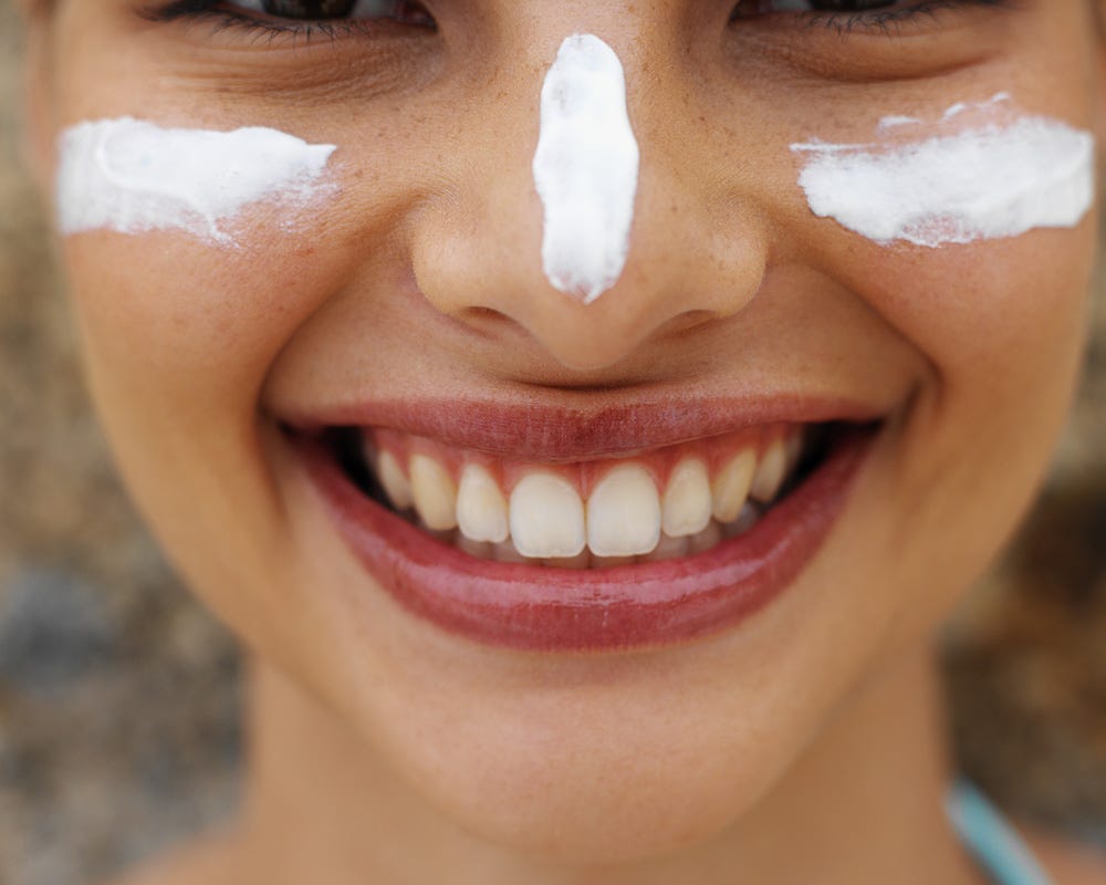 A girl with lines of sunscreen smeared on her face 