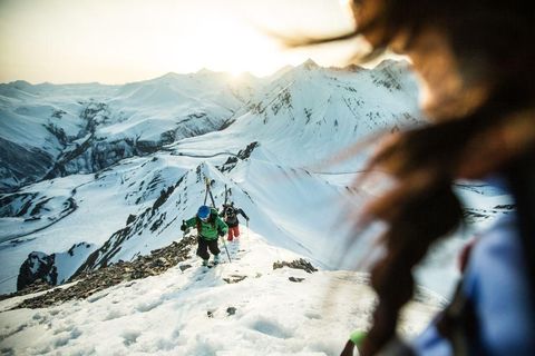 Ik was het wilde en afgelegen Kaukasusgebergte van Georgi aan het verkennen met een groep van pro ski freeriders Hier zie je de drie vrienden op een eenzame berg bij zonsondergang wandelen op een ongebaand pad naar de vallei Anne Wangler is al bij de top en kijkt hoe haar vrienden de laatste meters naar de berg lopen