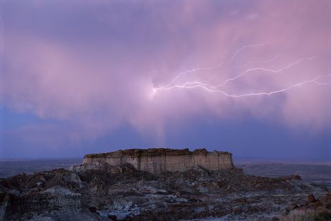 Boven een heuvel in de Red Desert van Wyoming schiet een vaag bliksemspoor s avonds door de wolken