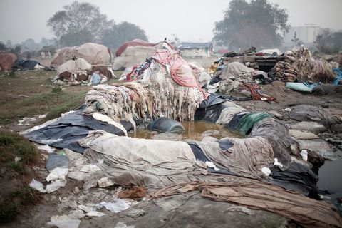 Stapels wasgoed uit hotels liggen in de modder langs de Yamunarivier