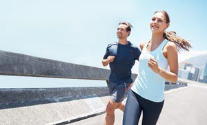 shot of two young runners training together on the road