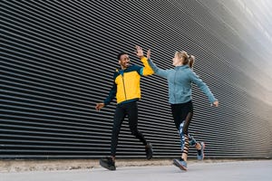 valencia, spain two young male and female athletes running together in the city past a black wall