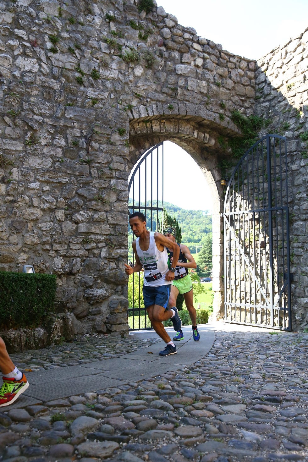 Runners passing through a stone archway