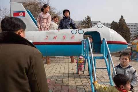 Schoolkinderen klauteren over een glijbaan in een speeltuin dat moet lijken op een NoordKoreaans vliegtuig