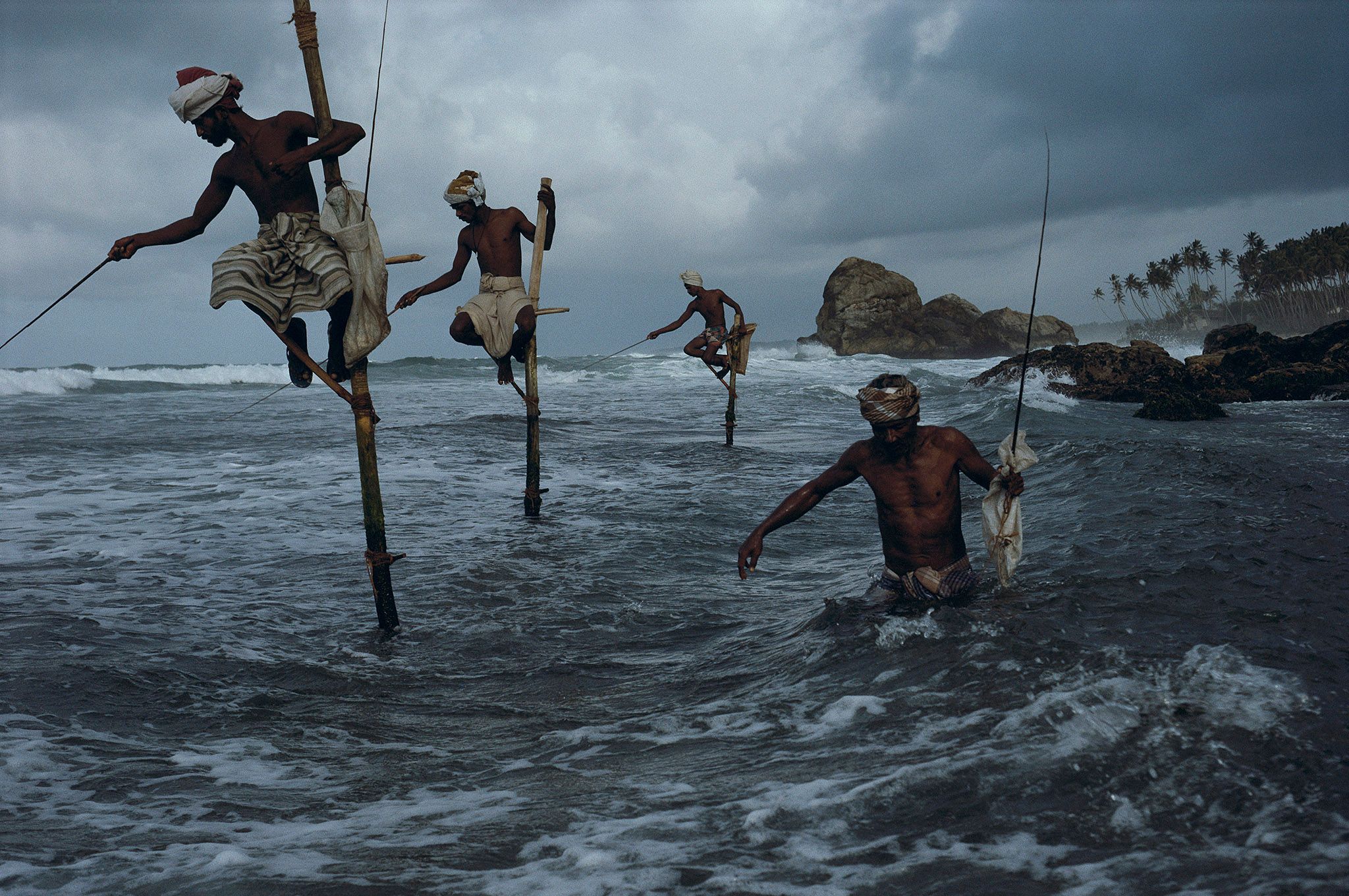 Mannen op houten stelten vissen aan de zuidkust van Sri Lanka
