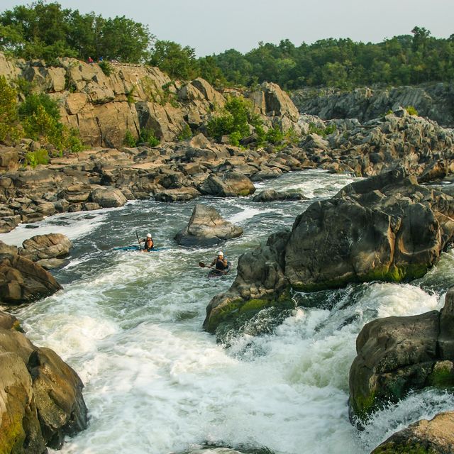 whitewater kayakers paddling down a series of small waterfalls