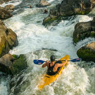 whitewater kayakers paddling down a series of small waterfalls