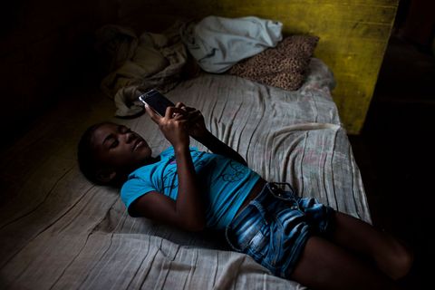 Een meisje speelt met de telefoon van haar moeder Sinds er internet op het eiland is brengen de meeste kinderen en tieners hun tijd door op een smartphone