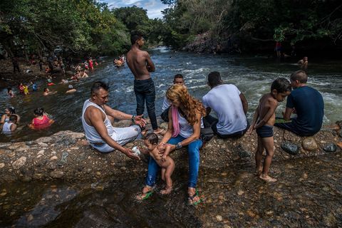 Esperanza laat haar dochtertje Desiree pootjebaden in de rivier La Rancherias tijdens een uitje met nieuwjaar Dit was het eerste uitstapje als burgers voor de voormalige FARCrebellen die in de overgangszone in Pondores wonen