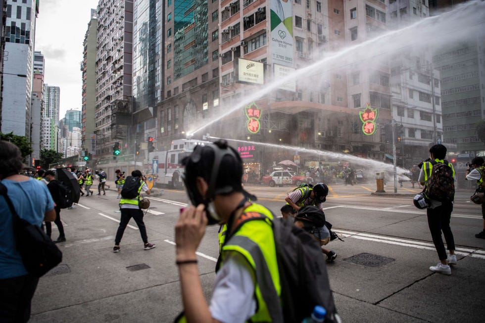 Een dag nadat China een nieuwe veiligheidswet afkondigde waarmee het land de demonstraties in Hongkong de facto onwettig heeft verklaard werd de jaarlijks mars voor de democratie in de stad door de politie verboden Op de foto duiken journalisten in gele hesjes weg voor een straal uit een waterkanon waarmee de politie demonstranten en omstanders probeert te verjagenUitHongkongers rouwen om de beindiging van hun levenswijze nadat China demonstraties heeft verboden