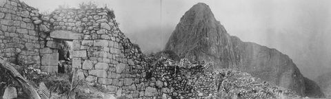 De hoofdpoort en interne stadsmuur van Machu Picchu met uitzicht op de Huayna Picchu