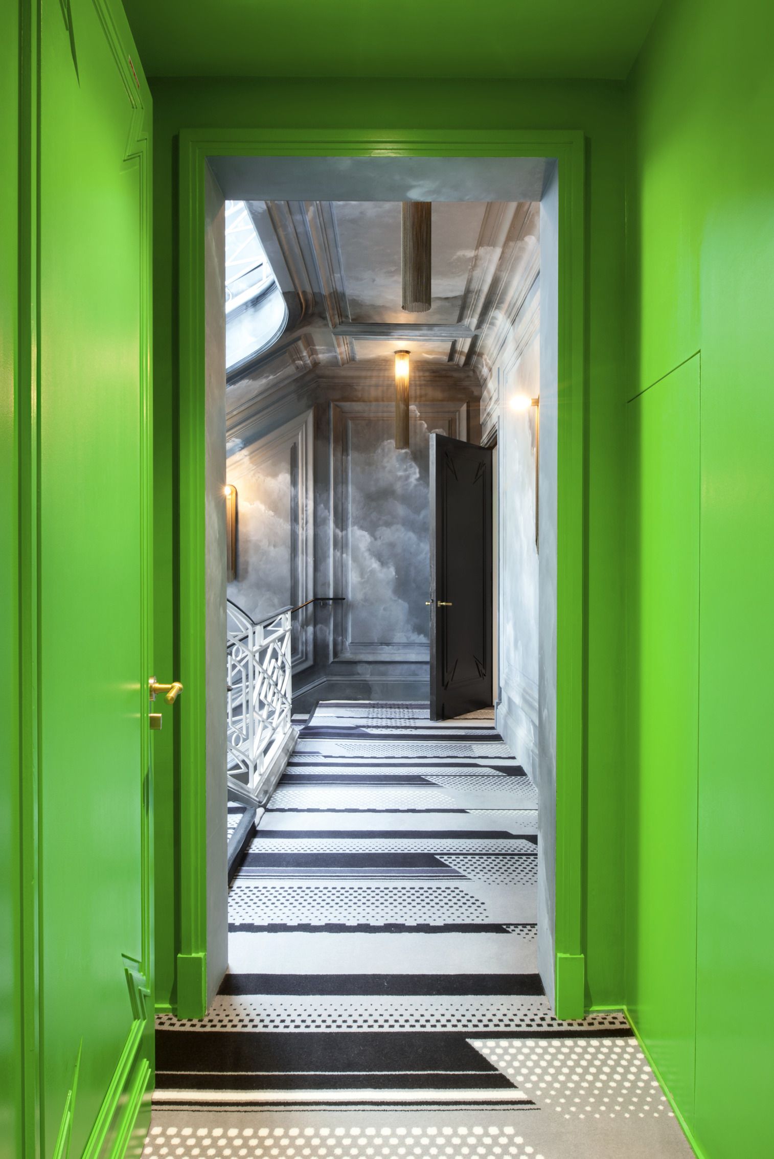 A List 2022 - ELLE DECOR corridor with acid green walls and geometric black and white floors and cloud painting on wall at far end