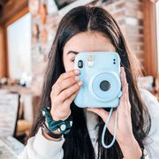 adolescent girl using a blue instant camera