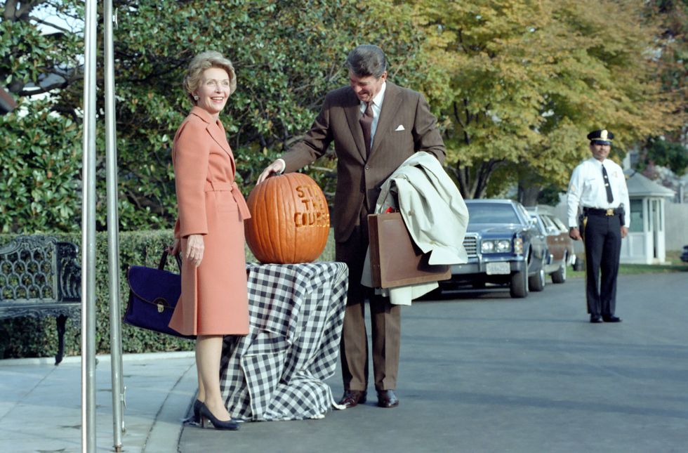 in this photograph, president ronald reagan admires a pumpkin carved with the slogan "stay the course" president reagan used the slogan during the 1982 midterm elections first lady nancy reagan poses alongside the pumpkin the two are standing outside the south portico entrance to the white house