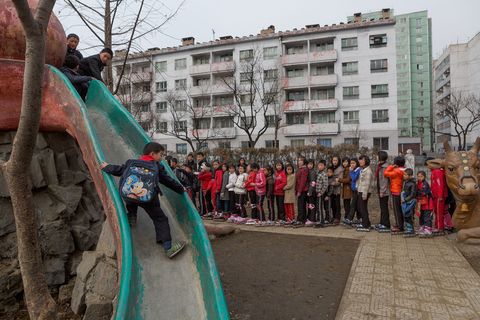 Een jongetje klimt op een glijbaan terwijl skaters toekijken Sommige westerse iconen  zoals Mickey Mouse op de rugzak van het jongetje  zijn zo doordringend dat ze zelfs de afgesloten wereld van NoordKorea bereiken
