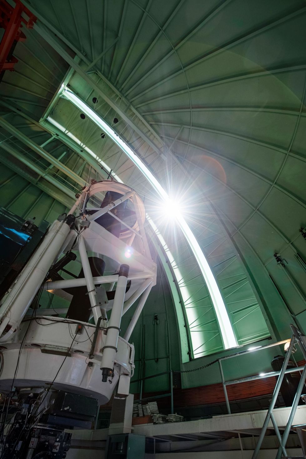 De zon schijnt door een spleet in de koepel van de Vctor M Blancotelescoop die deel uitmaakt van het Cerro Tololo InterAmerican Observatory in Chili Met de Dark Energy Camera op deze 4metertelescoop wordt gezocht naar schemerasteroden in het binnenste zonnestelsel