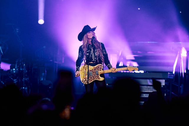 musician performing on stage with a guitar under colorful lights