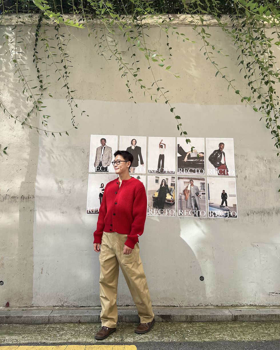 a man standing next to a wall with pictures on it