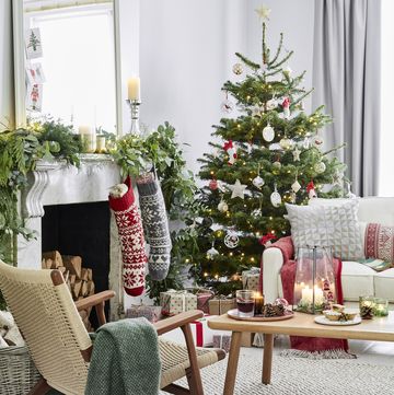 living room, with a christmas tree and stockings on the fireplace candles in lanterns on the wooden coffee table logs stacked in the fireplace
