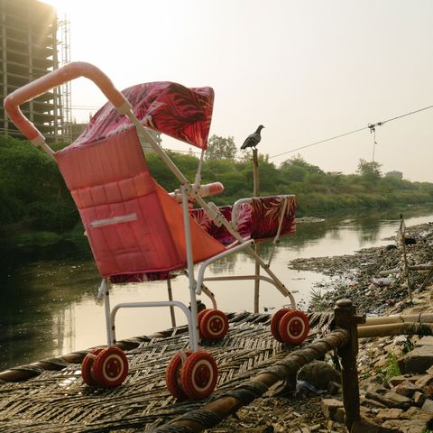 Een schoongemaakt wandelwagentje staat naast het Shahadrariool waar veel verarmde inwoners van Delhi gemproviseerde hutjes hebben opgetrokken