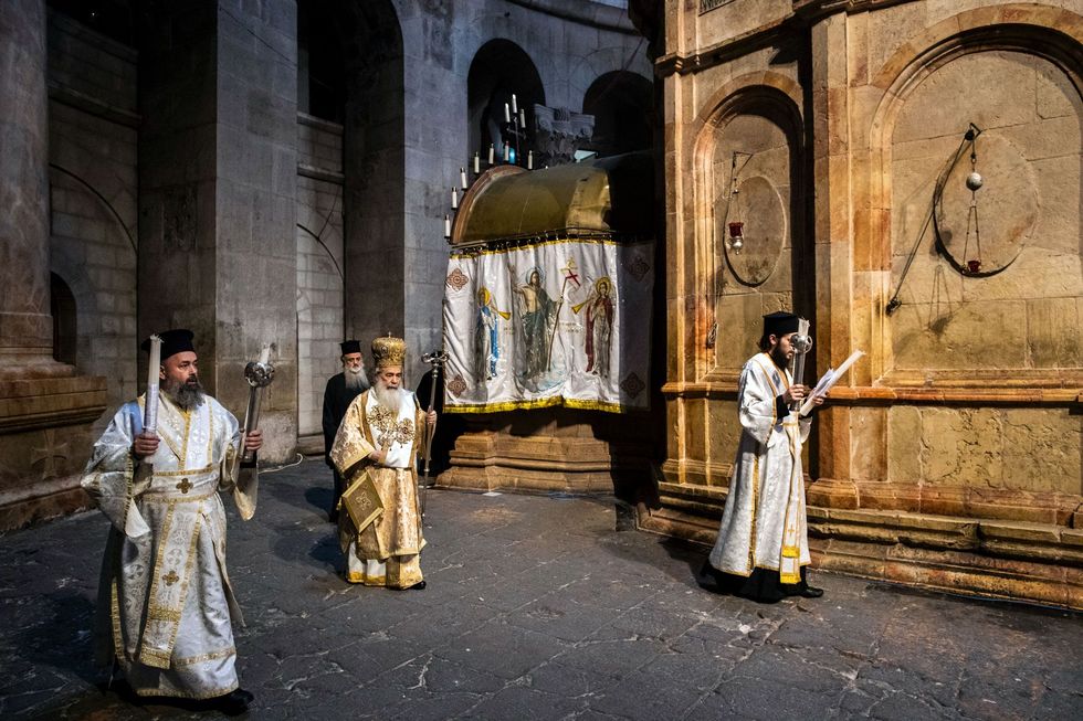 Theofilus III de GrieksOrthodoxe patriarch van Jeruzalem midden loopt in een lege kerk om de Aedicula heen voordat de Heilig Vuurceremonie kan beginnen