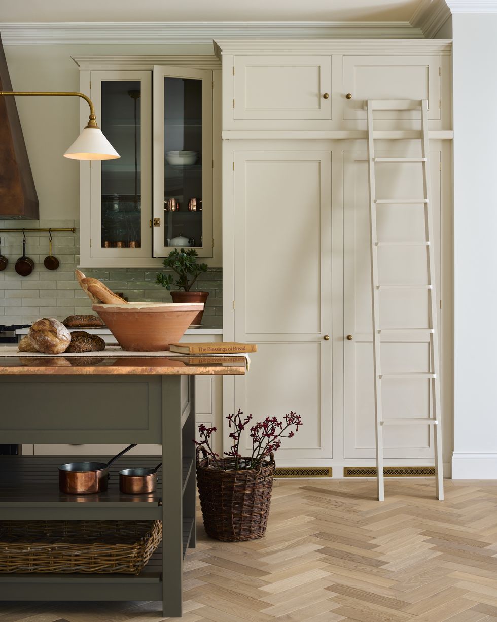 a kitchen with wooden flooring and tall cream cabinets with a ladder