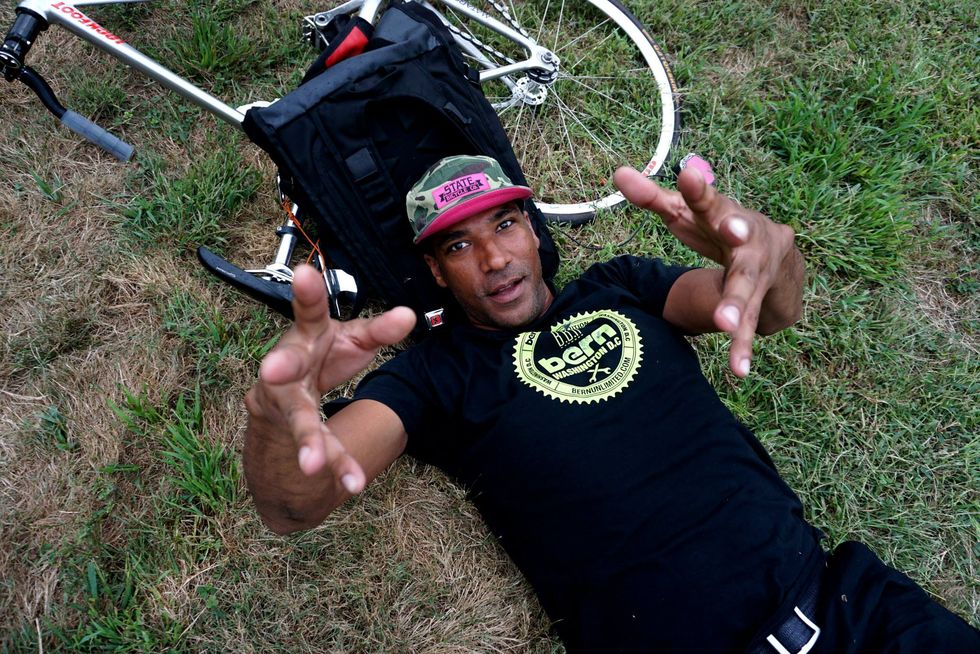 david confer laying on the ground next to his track bike, reaching out to the camera