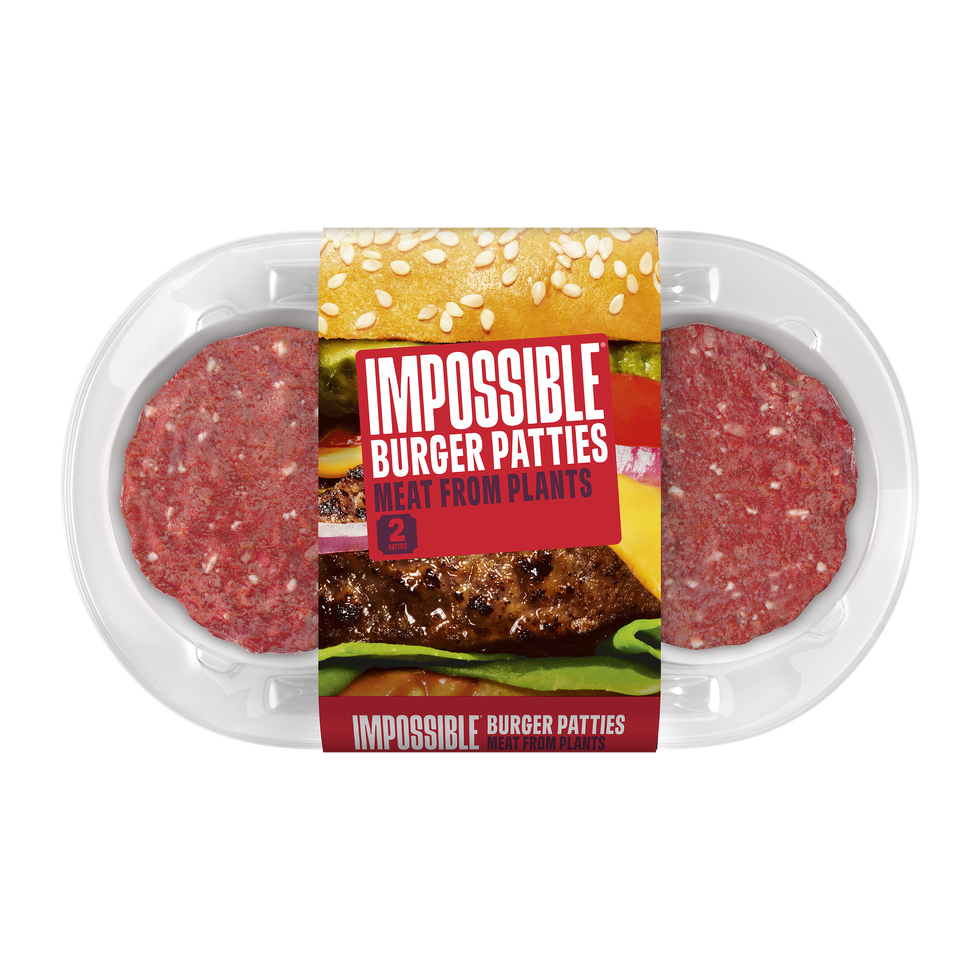 two raw burger patties made from plant based ingredients, positioned in a white tray the packaging features a prominent label that highlights the product name, 'impossible burger patties,' and emphasizes that the meat is derived from plants the tray showcases a sesame seed bun along with various colorful toppings, such as lettuce, tomatoes, and pickles, hinting at potential burger assembly