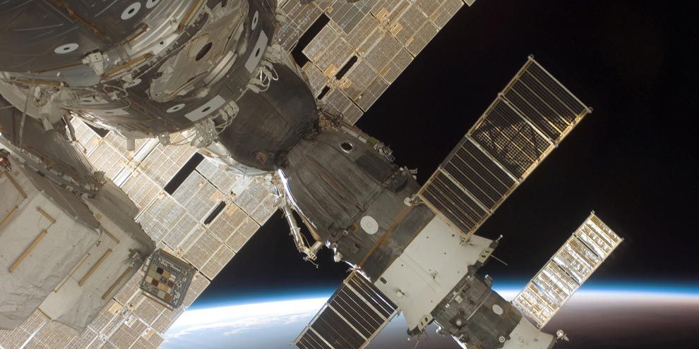 De inktzwarte ruimte en de atmosfeer van de aarde vormen de achtergrond voor deze opname van een aangekoppelde Soyuz 13 op de voorgrond en het bevoorradingsvaartuig Progress 22 Astronauten fotografeerden de Soyuz door een venster van het ISS terwijl de spaceshuttle Discovery aan het ruimtestation was aangekoppeld